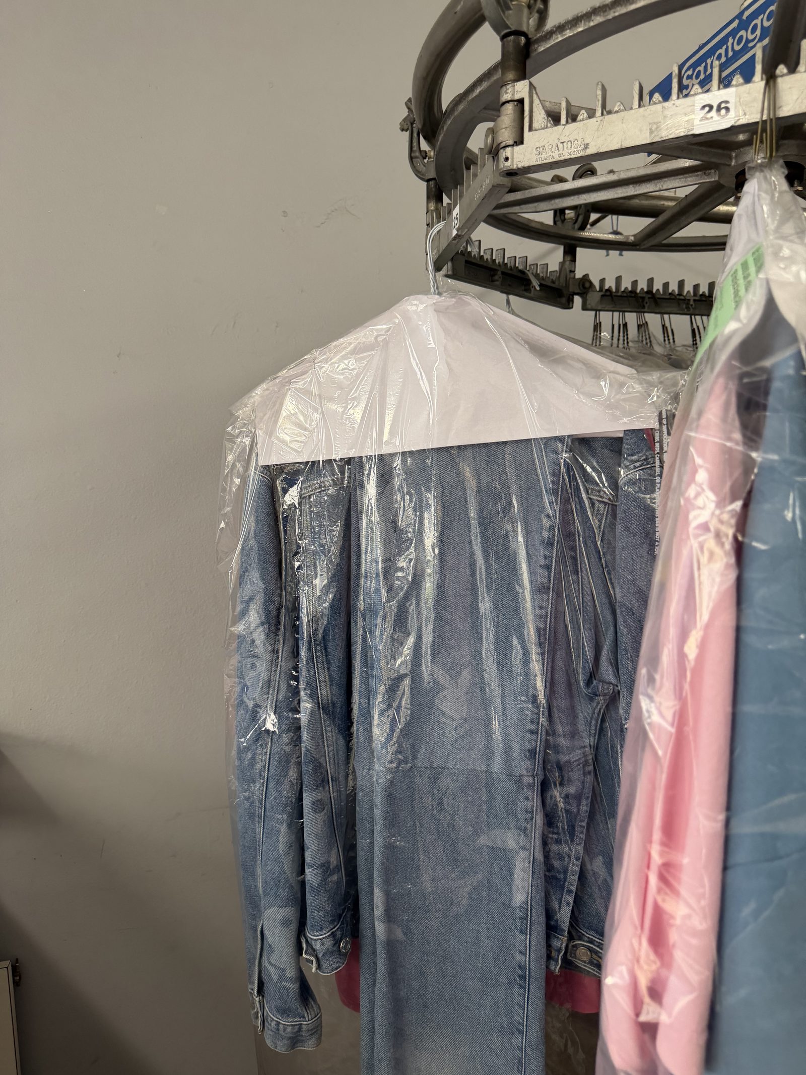 FOLD dry-cleaning detail — bagged denim jacket on Saratoga overhead conveyor at our owned LA facility