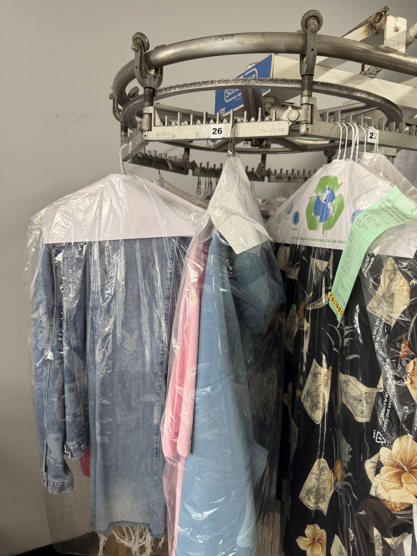 FOLD's finished dry-cleaned items on the overhead conveyor &mdash; we own the operation, no subcontracting